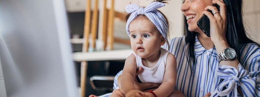 A woman holding a baby while talking on the phone.