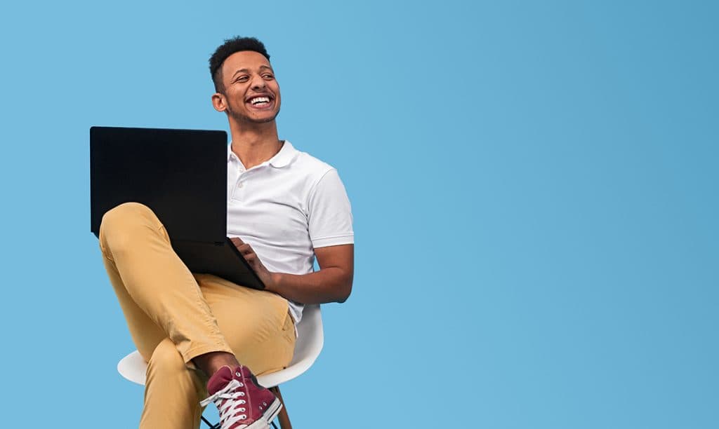 Cheerful black student with laptop looking away