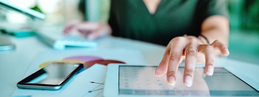 A woman is using a tablet on a desk.