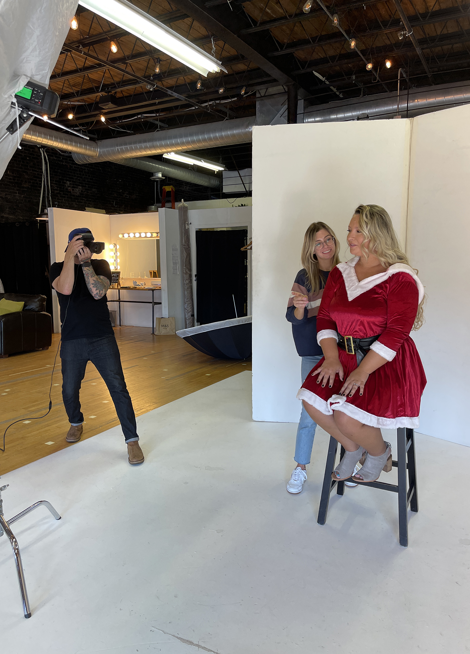 A woman in a santa claus costume sitting on a stool.