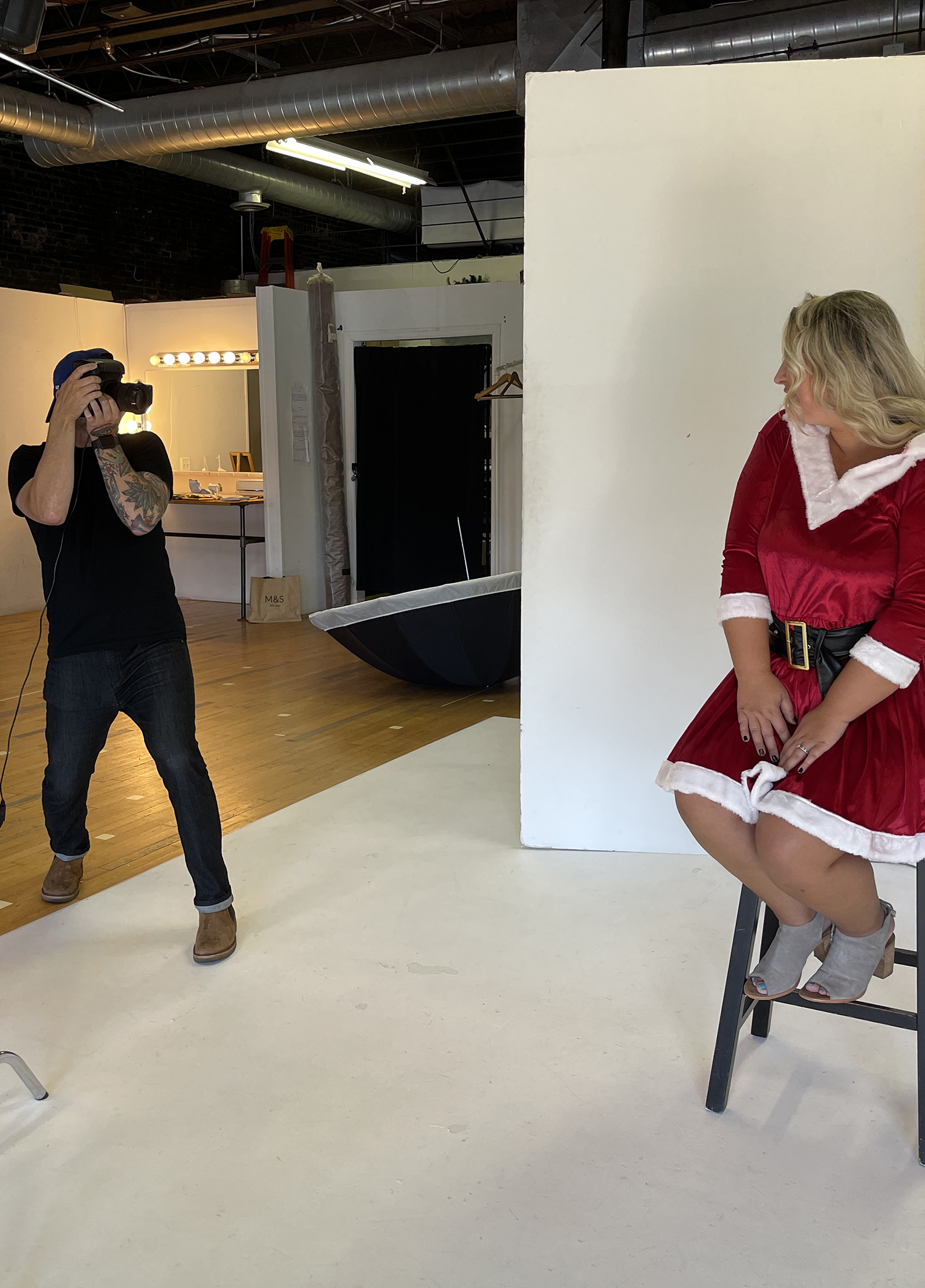 A woman in a santa claus costume sitting on a stool.