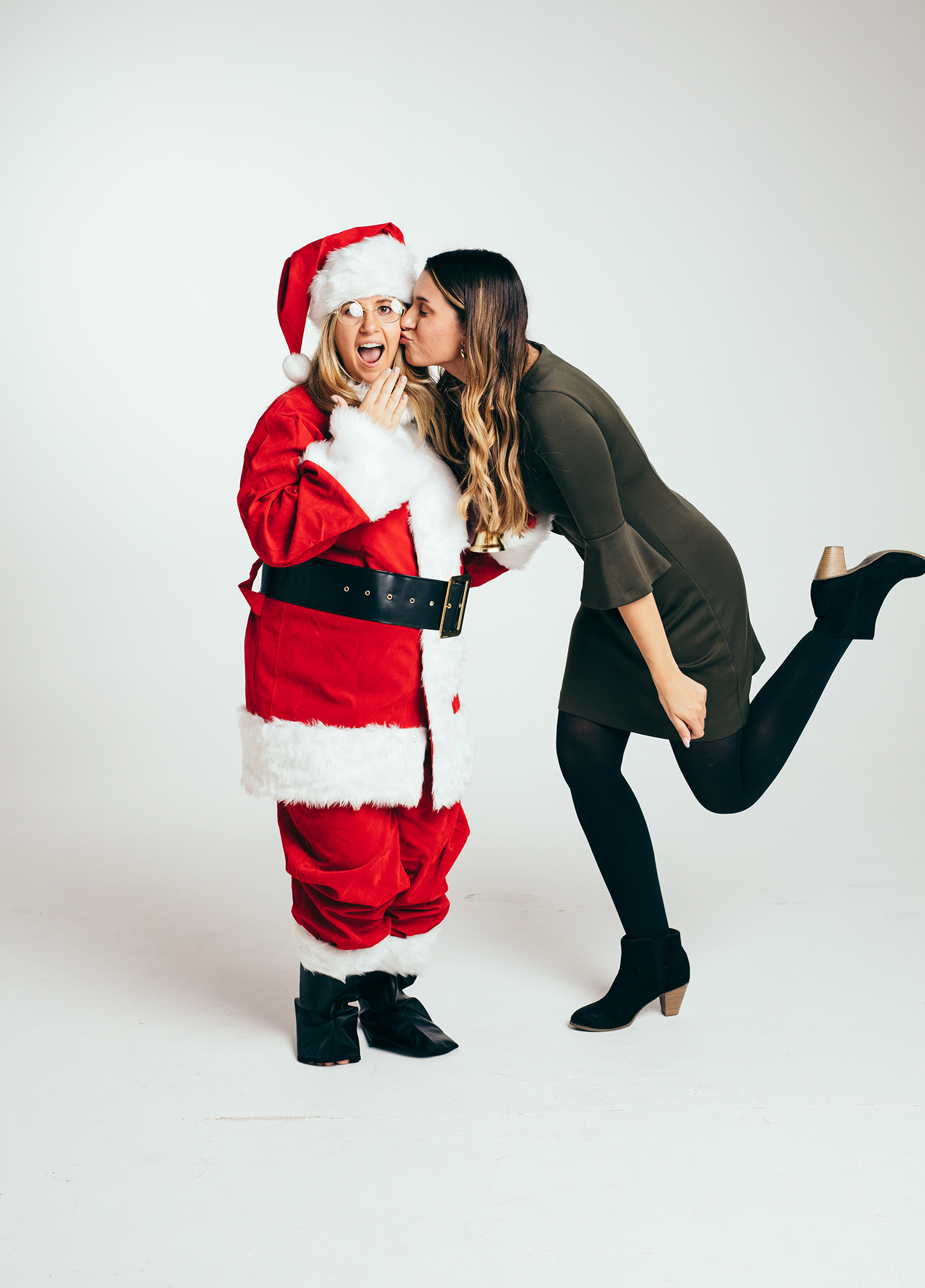 A woman kissing a santa claus in a studio.