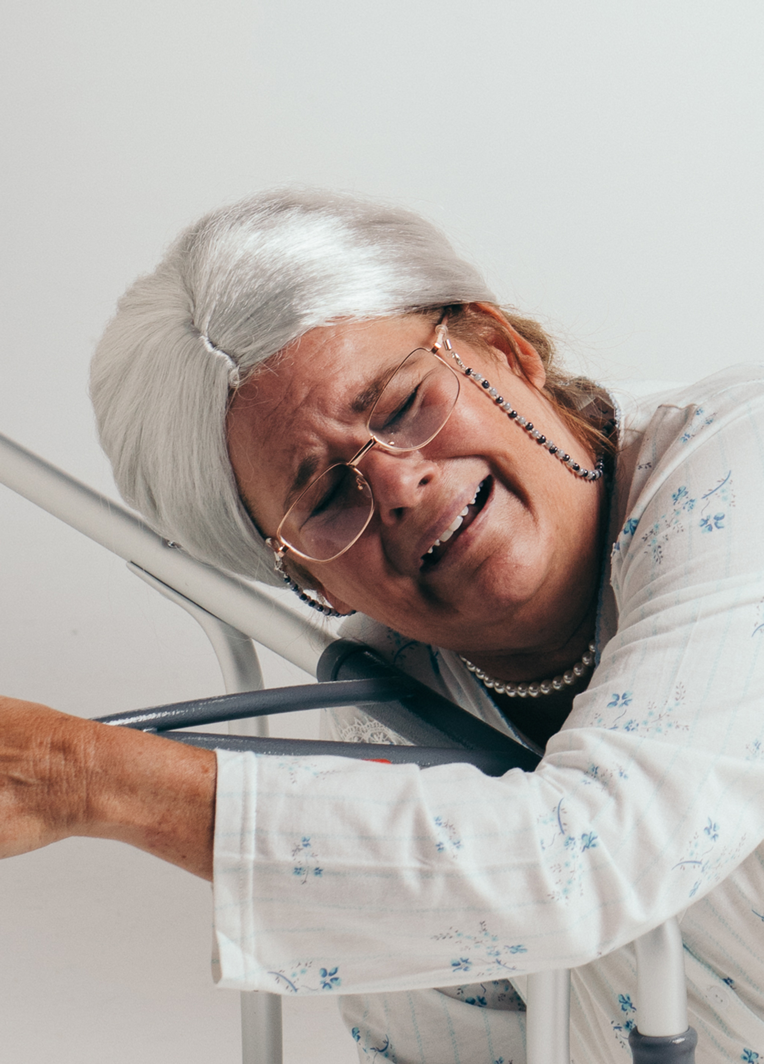 An elderly woman leaning on a walker.