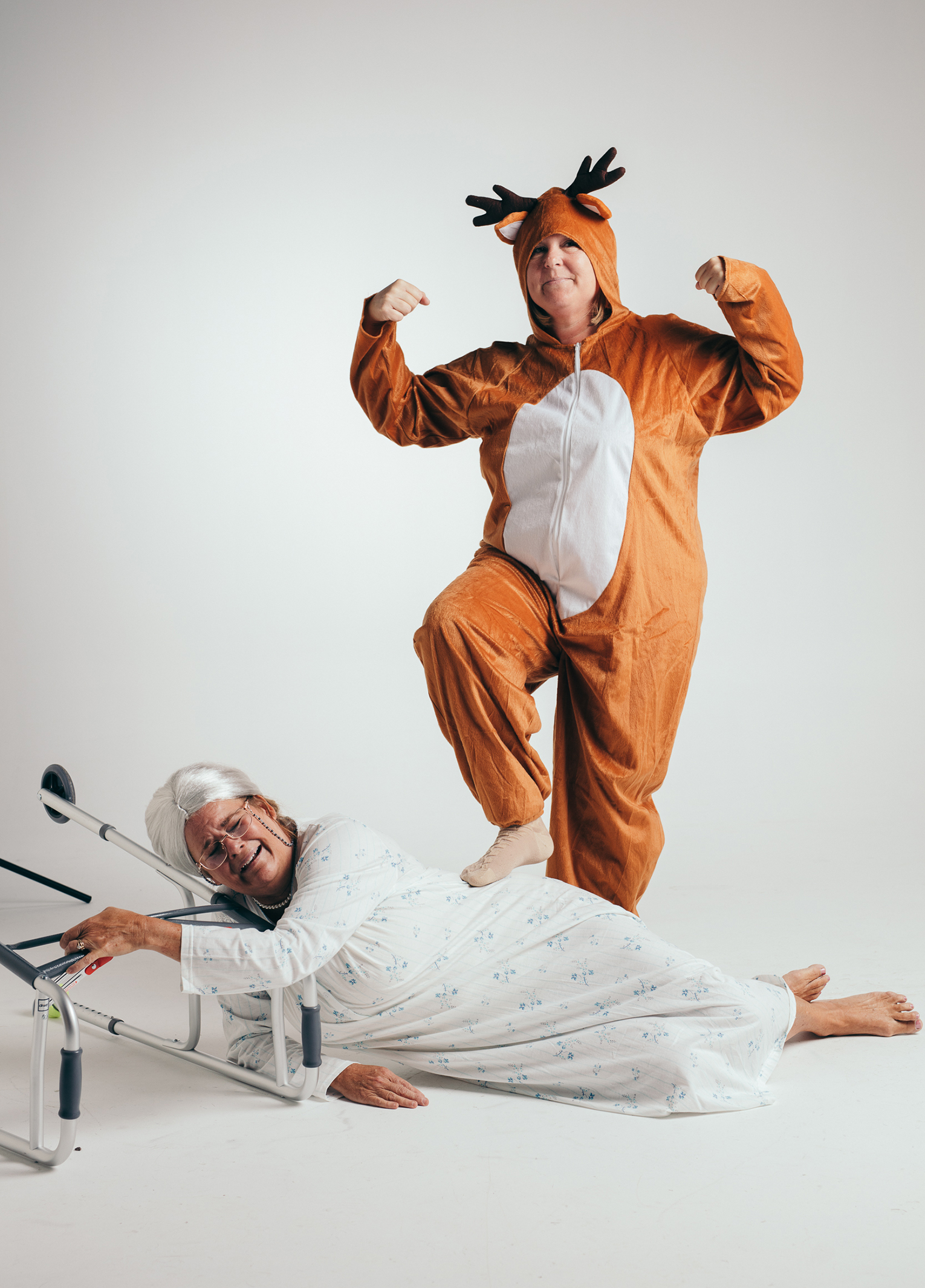 Two people dressed as reindeer laying on a bed.