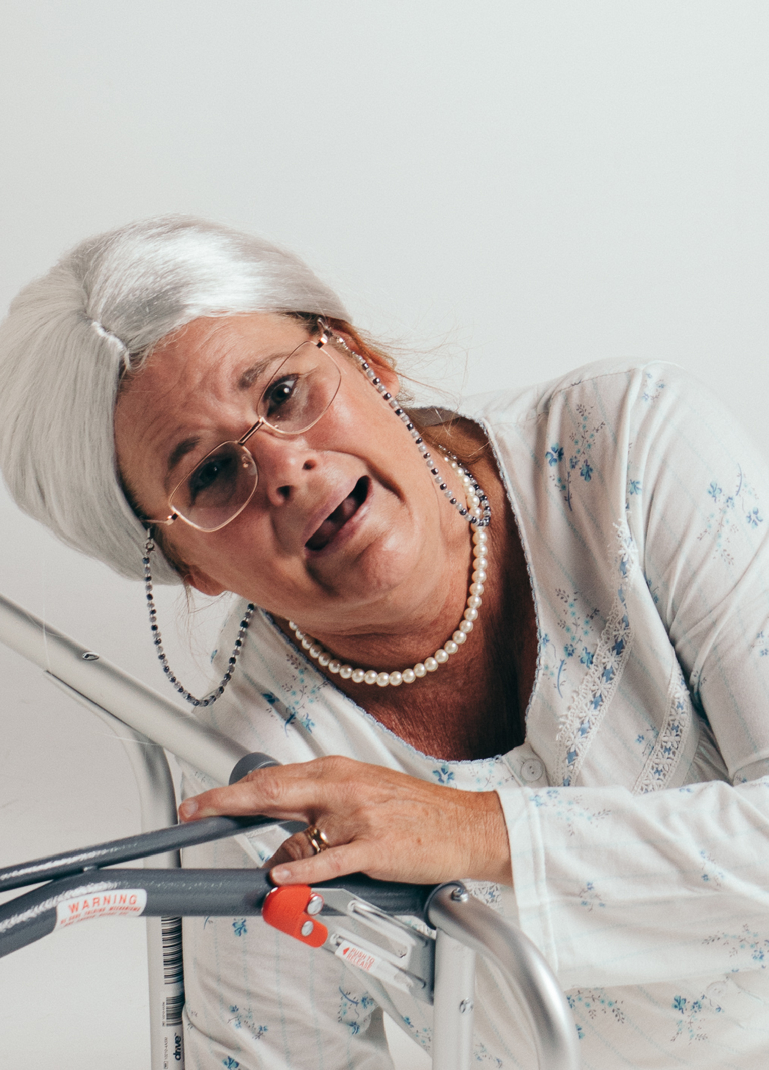 A woman with white hair and a pearl necklace.