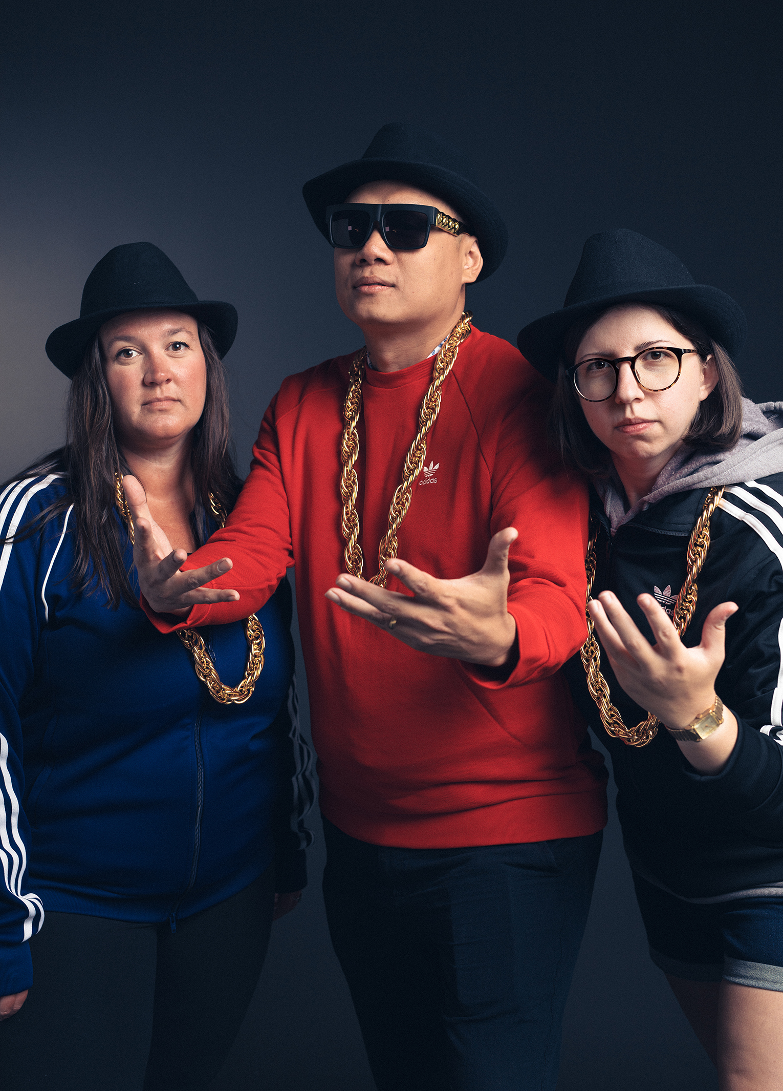 Three people posing for a photo with hats and chains.