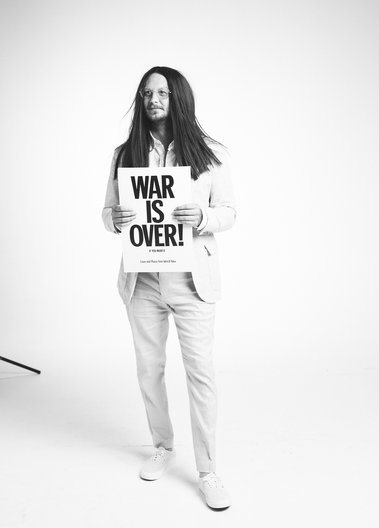 A man holding a sign that says war is over.