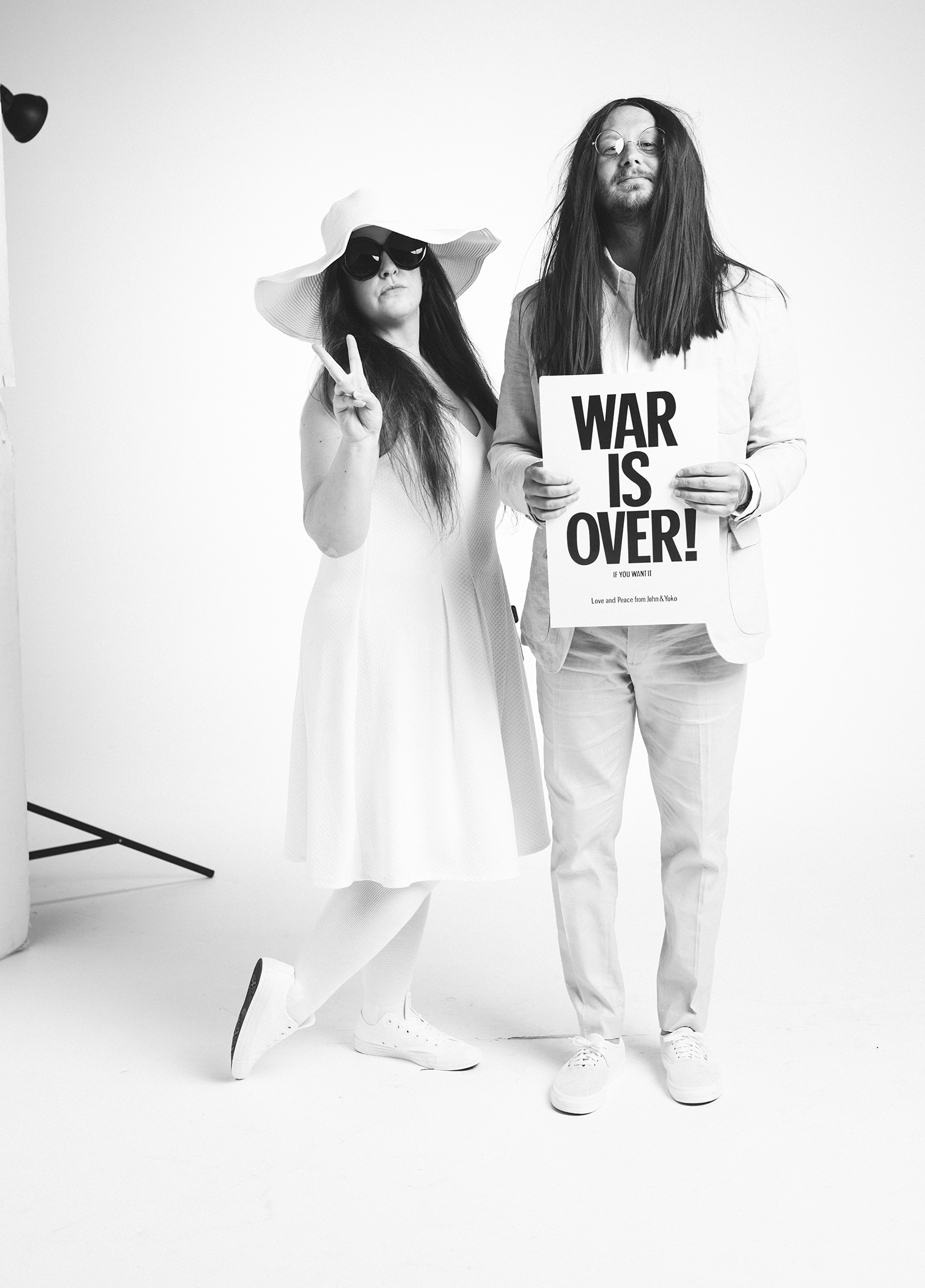 Two people posing for a photo with a sign that says war over.