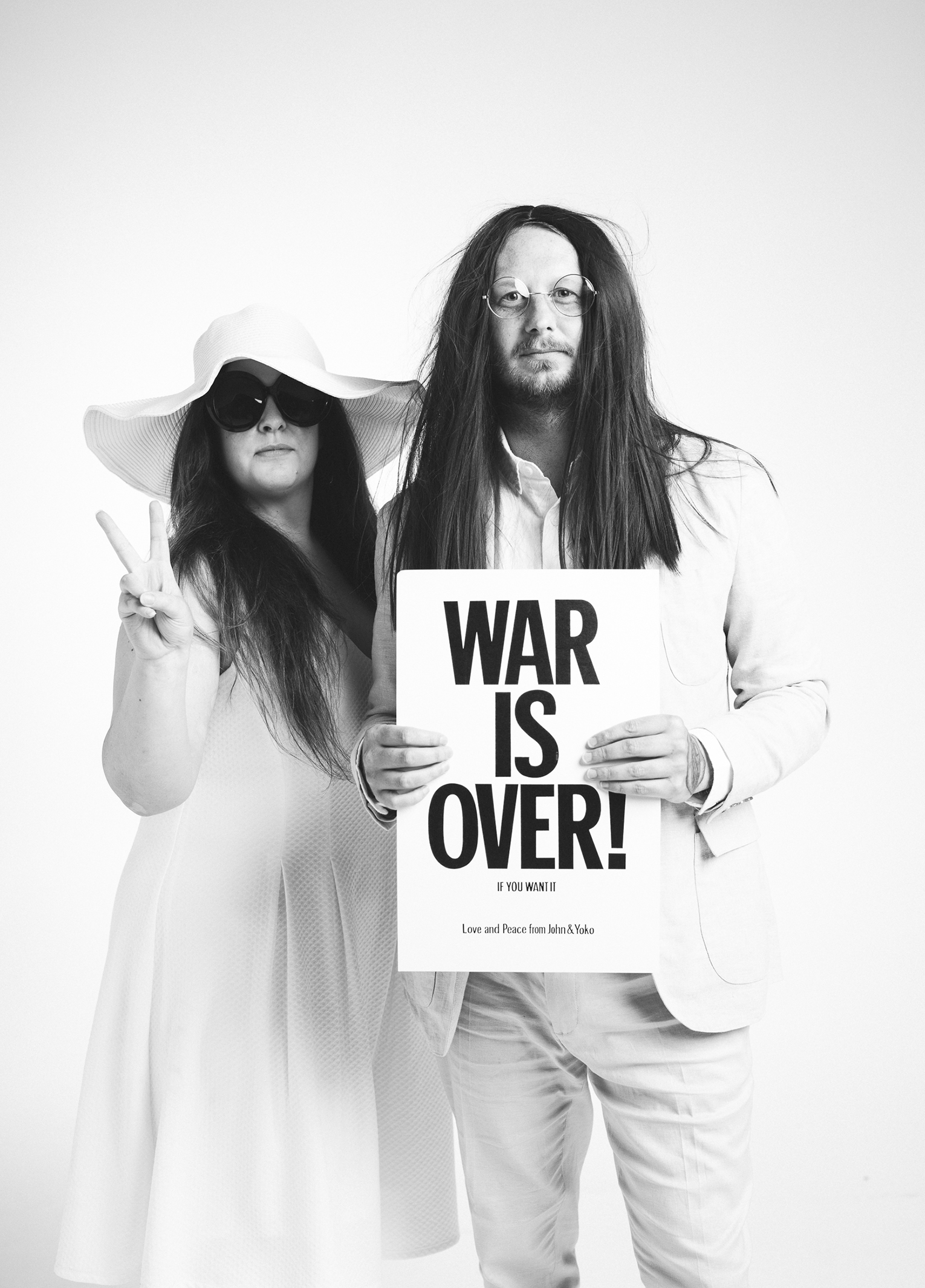 A man and woman holding a sign that says war is over.