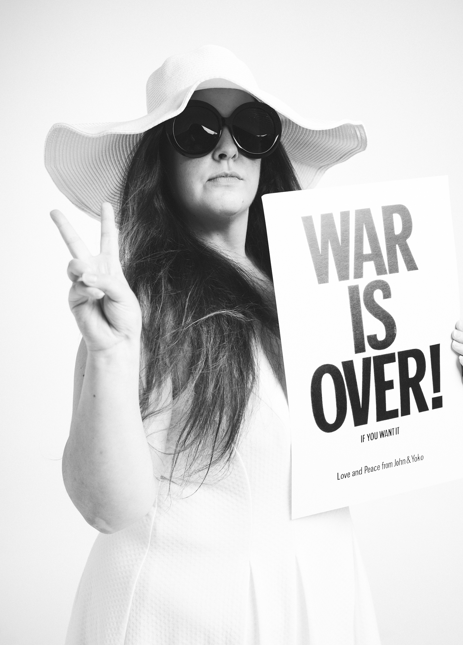 A woman holding a sign that says war is over.