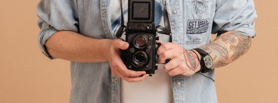 A man with tattoos holding a camera.
