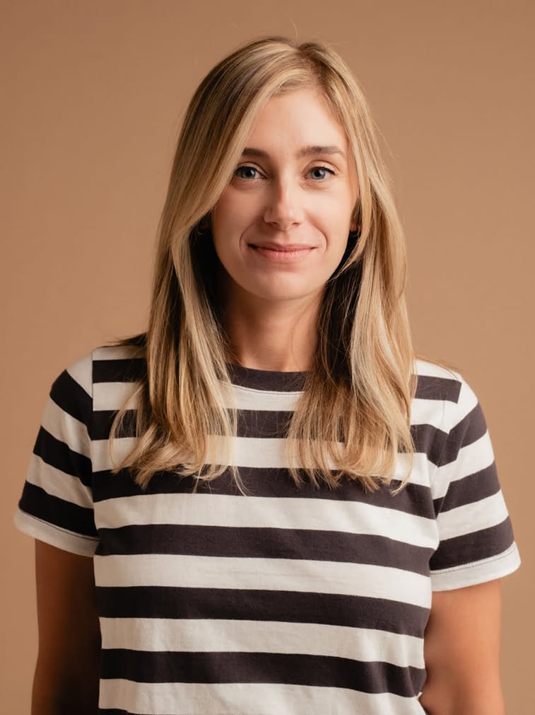 A woman wearing a black and white striped t - shirt and white jeans.